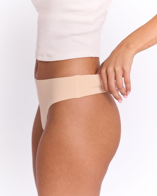 Close up side view of a woman modelling Trelou's active underwear, wearing a white tank top.